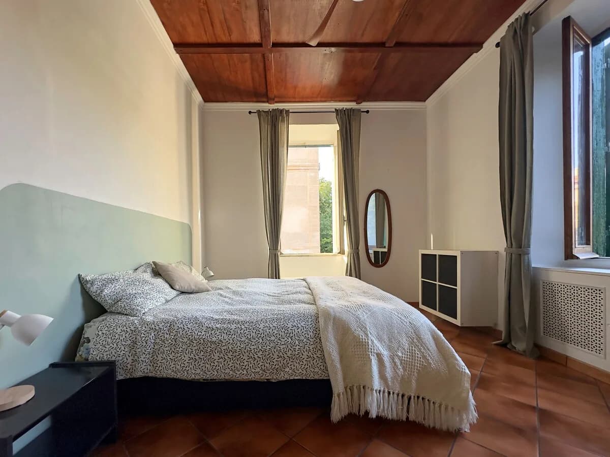 Camera matrimoniale con soffitto in legno e due finestre